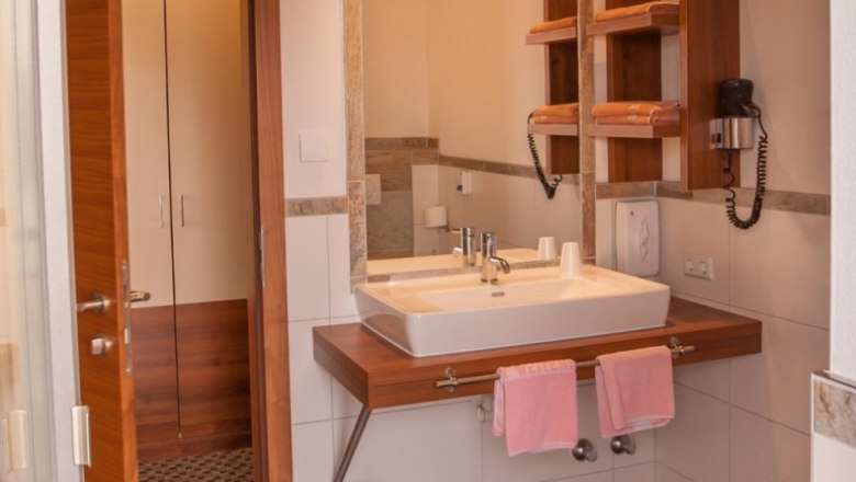 Badezimmer 2, © wirtshausgruber.at Modernes Badezimmer mit Waschbecken, Spiegel, Handtüchern und Föhn.