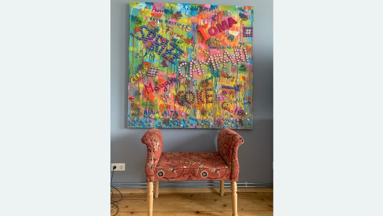 Kunst im Haus Zwei, © Familie Wochesländer Buntes Gemälde mit Schriftzügen über einer roten Bank.