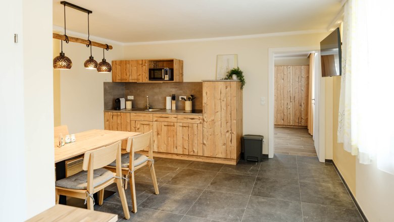 Küche Gelber Muskateller, © Michael Reidinger Moderne Küche mit Holzmöbeln und Esstisch, helle Beleuchtung.