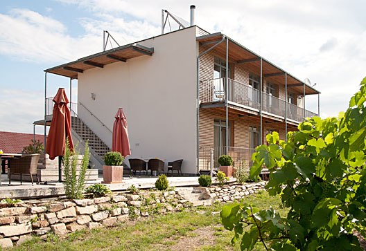 Aussenansicht mit Garten, © Weinresidenz Sonnleitner Modernes Gebäude mit Terrasse und Garten im Vordergrund.