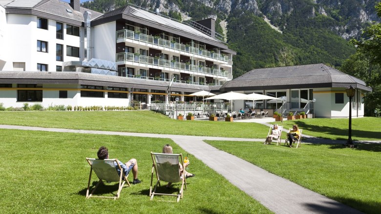Parkhotel Hirschwang, © Parkhotel Hirschwang Parkhotel Hirschwang mit Liegestühlen auf einer grünen Wiese und Bergen im Hintergrund.