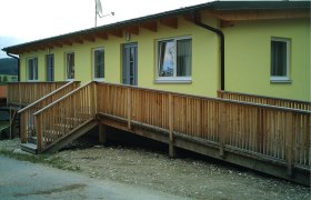 Gasthof Christiane Winter, © Gasthof Christiane Winter Gelbes Gebäude mit Holzrampe und Fenstern.