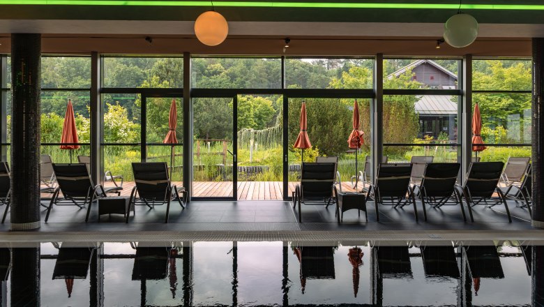 Hotel & Spa Linsberg Asia, © Niederösterreich Werbung / Maximilian Pawlikowsky Innenansicht eines Spas mit Liegestühlen und Blick auf einen Garten durch große Fenster.