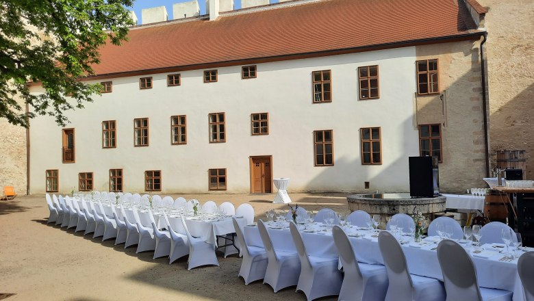 Tafeln im Weinviertel, © Weinviertel Tourismus GmbH Langer Tisch mit weißen Stühlen in einem historischen Innenhof.