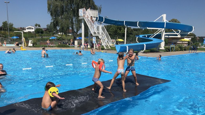 Freibad Neuhofen an der Ybbs, © Gemeinde Neuhofen Kinder spielen im Freibad Neuhofen an der Ybbs auf einer schwimmenden Matte vor einer Wasserrutsche.