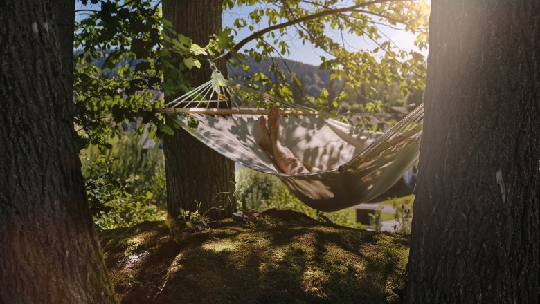 Aigen13, © MATHIAS LIXL / lixl.com Person entspannt in einer Hängematte zwischen Bäumen im Wald.