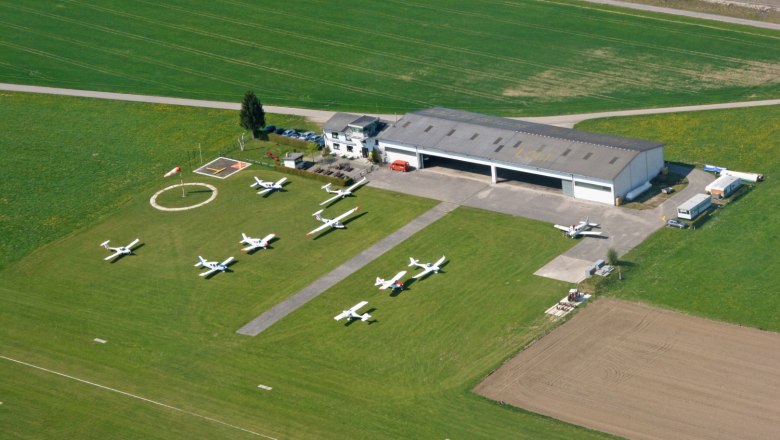 Flugunion Seitenstetten-Biberbach, © Ewald Grabner Luftaufnahme eines kleinen Flugplatzes mit mehreren geparkten Flugzeugen und einem Hangar.