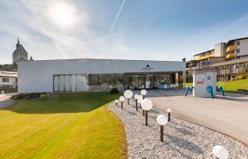 Sconarium und Wehrkirche Bad Schönau, © Wiener Alpen, Christian Kremsl Außenansicht des Sconariums in Bad Schönau bei Sonnenschein, Wehrkirche im Hintergrund