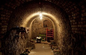 Kelleröhre, © Weinviertel Tourismus / Wurnig Ein schmaler, gewölbter Weinkeller mit Ziegelwänden und gelagerten Flaschen.