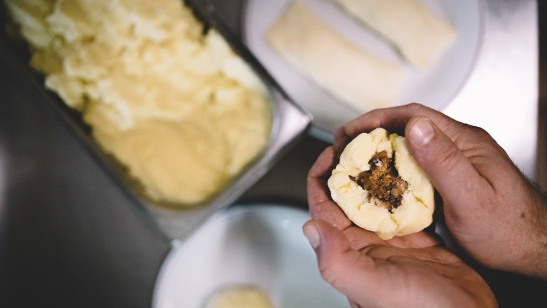 1. Wirtshausknödelmanufaktur ®, © Niederösterreich Werbung/Mara Hohla Hände formen einen gefüllten Knödel aus Teig.