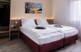 Doppelzimmer, © W. Garhöfer Modernes Doppelzimmer mit zwei Einzelbetten, Bild an der Wand, Kleiderschrank und Fenster mit Vorhängen.