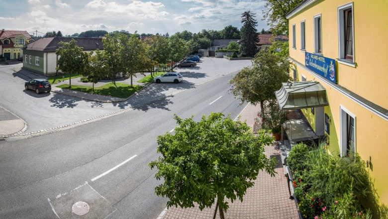 Auland-Hotel Siebenbrunnerhof, © Auland-Hotel Siebenbrunnerhof Straßenszene mit gelbem Gebäude und Parkplatz, Bäume und Autos.