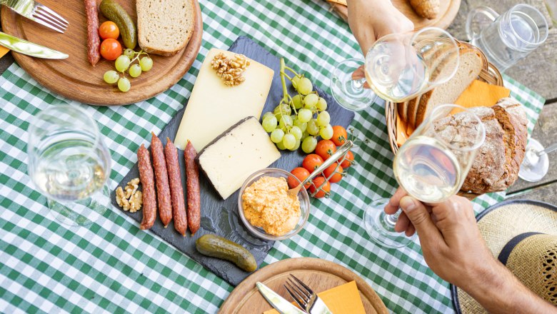 Heurigenjause, © Weinviertel Tourismus GmbH / Schwarz-König Picknicktisch mit Käse, Wurst, Brot und Wein auf kariertem Tuch.
