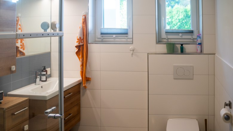 Badezimmer, © Peter Wochesländer Modernes Badezimmer mit Dusche, Waschbecken, Toilette und zwei Fenstern.