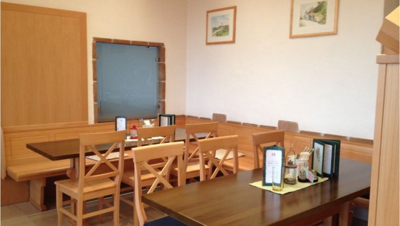 Heuriger Schauhuber, © Daniela Schauhuber Innenraum Heuriger Holztische mit Sesseln