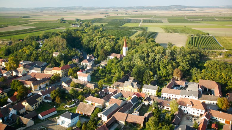 Blick über Königsbrunn, © Gemeinde Königsbrunn am Wagram Luftaufnahme eines Dorfes mit Kirche und umliegenden Feldern.
