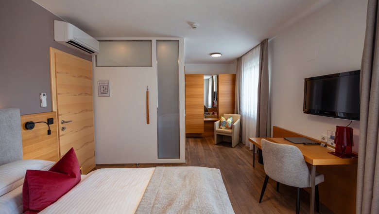 Weindomizil Hagn, © Niederösterreich Werbung / Maximilian Pawlikowsky Modern eingerichtetes Hotelzimmer mit Bett, Schreibtisch, Stuhl und Fernseher.