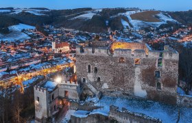 Burgruine Kirchschlag, © Wiener Alpen, Foto: Walter Strobl Burgruine Kirchschlag bei Dämmerung mit beleuchteter Stadt im Hintergrund.