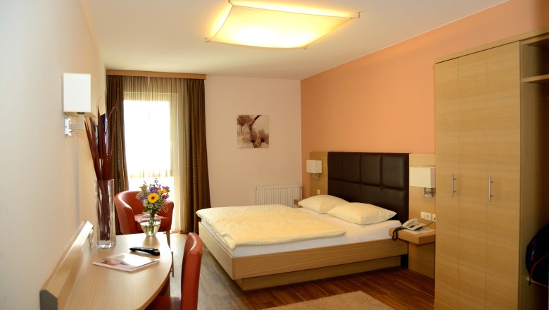 Hotel-Gasthof Graf, © Fam. Graf Ein modernes Hotelzimmer mit Doppelbett, Schreibtisch, Stuhl und Blumenstrauß auf einem Tisch.