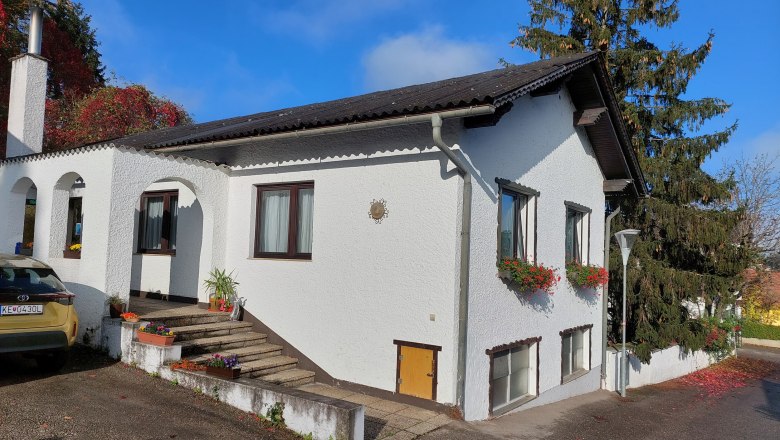 TDR-Welserhof-außen, © Nora Bartfai Ein weißes Haus mit Blumen an den Fenstern und einem Auto davor.