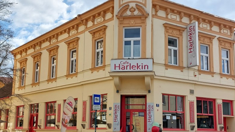 Cafe Restaurant Harlekin, © Weinviertel Tourismus Außenansicht des Cafe Restaurant Harlekin mit gelber Fassade und roten Fenstern.