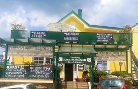 Gasthaus zum Kirchenwirt in Schwarzenbach, © Wiener Alpen Gelbes Gasthaus mit grüner Beschilderung von Tagesangeboten