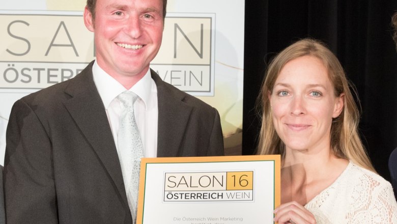 Winzerpaar, © Salon 16 Österreich Zwei Personen halten eine Urkunde mit der Aufschrift 'Weinbau Sepp Kohl' bei einer Veranstaltung.