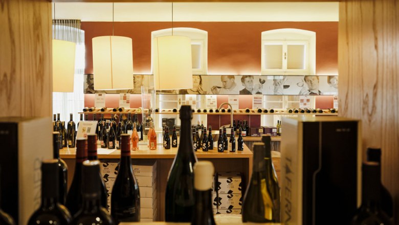 Vinothek im ersten Stock, © Niederösterreich Werbung/Michael Reidinger Innenansicht einer Vinothek mit Weinflaschen und dekorativen Lampen.