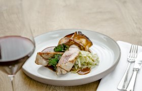 Herzlich Willkommen, © Weinviertel Tourismus / Astrid Bartl Ein Teller mit Fasanbrust, Grünkohl und Kraut, daneben ein Glas Rotwein.