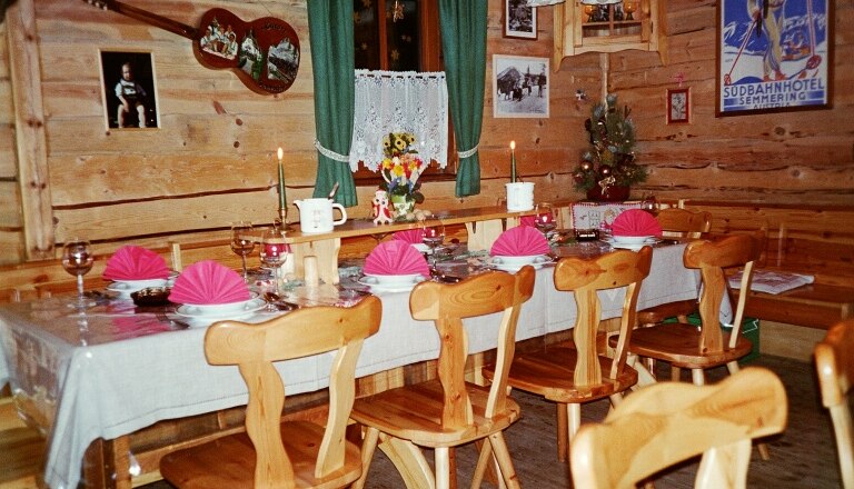Grenzlandhütte, © Grenzlandhütte, Foto Paul Laschitz Gemütliche Holzhütte mit gedecktem Tisch, Kerzen, Dekorationen und Bildern an den Wänden.