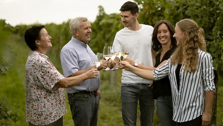 walzer-johann-20, © Weinbau Johann Walzer Fünf Personen stoßen mit Weingläsern in einem Weinberg an.