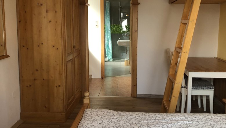 Zimmerdurchgang Urlaub am Jauerling, © Romana Wiener Innenansicht eines Zimmers mit Holzmöbeln und einem Durchgang zu einem Badezimmer.