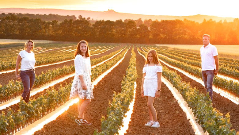 Familie Schwalm, © Familie Schwalm Eine Familie steht in einem Feld bei Sonnenuntergang.