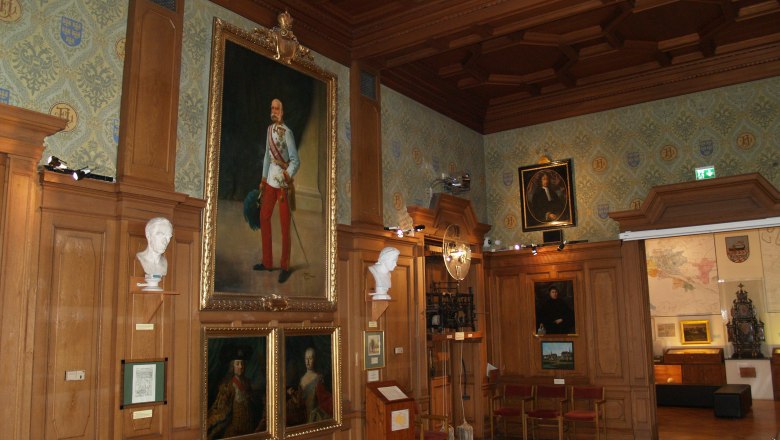 Grosser Saal, © Rollettmuseum Ein historischer Saal mit Holzvertäfelung, Gemälden und Büsten an den Wänden.