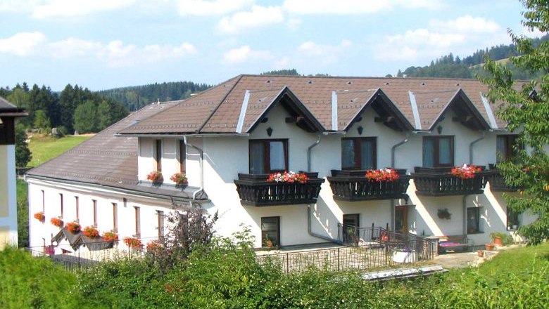 Angerhof, © Buchinger Ein großes, weißes Gebäude mit braunen Dächern und Balkonen mit Blumen.