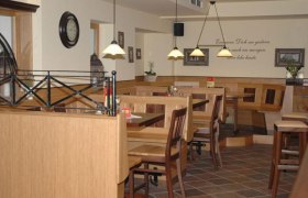 Gastraum, © Familie Schreiblehner Ein gemütlicher Gastraum mit Holzmöbeln, Tischen und Stühlen. An der Wand hängt eine Uhr und es gibt dekorative Pflanzen.