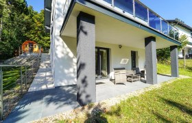 Ferienhaus Waxeneck, © Michaela Narath Terrasse eines modernen Ferienhauses mit Gartenmöbeln und angrenzendem Garten.