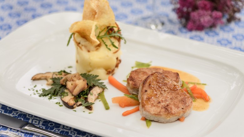 Genuss im Restaurant Loibnerhof, © Rita Newman Gourmetgericht mit Fleisch, Kartoffelpüree und Gemüse auf weißem Teller.