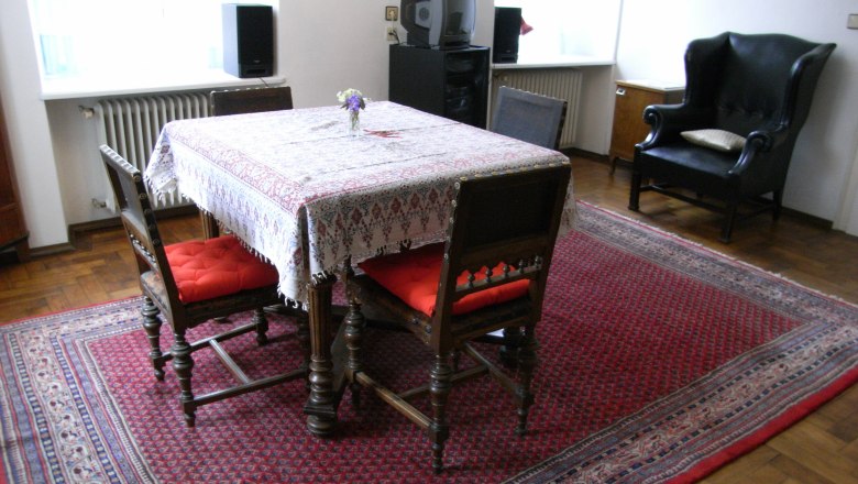 Wohnzimmer, © stein Wohnzimmer mit Tisch, Stühlen und Teppich.