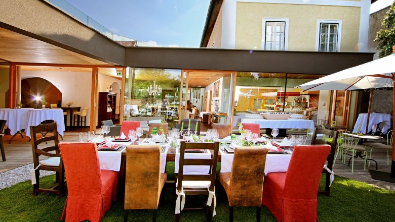 Tafel, © Hotel Landhaus Moserhof GmbH Elegantes Restaurant mit gedecktem Tisch im Freien, umgeben von modernen Gebäuden.