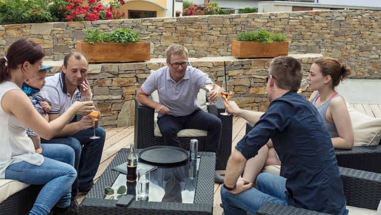 Feiern auf der Terrasse, © KASTNER NEW MEDIA - kastner.tv Gruppe von Menschen sitzt draußen auf einer Terrasse und stößt mit Getränken an.