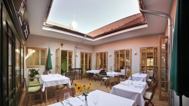 TDR-GWFloh innen, © Jürgen Skarwan Innenhof eines Restaurants mit gedeckten Tischen und offenem Dach.