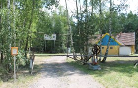 SOLA Langau, © Hannes Messmann Eingang zu einem Lagerplatz mit einem gelben Gebäude im Hintergrund.