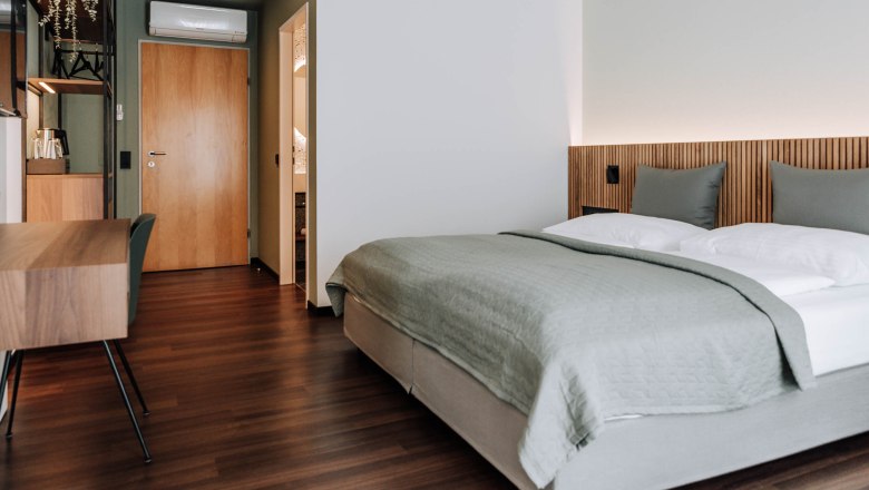 Comfort HEINhotel vienna airport, © HEINhotel vienna airport Modernes Hotelzimmer mit Doppelbett, Holzboden und Schreibtisch.