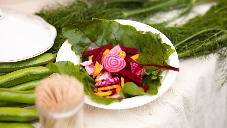 ARCHE NOAH, © ARCHE NOAH_Rupert Pessl Ein Teller mit geschnittenem Gemüse auf einem Tisch, umgeben von grünen Blättern und einem Glas mit Zahnstochern.