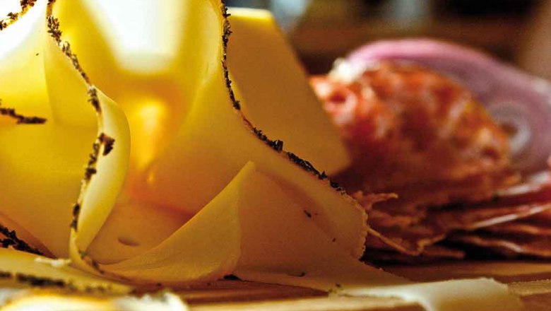 Speisen, © Egle Nahaufnahme von dünn geschnittenem Käse und Wurst auf einem Holzbrett.