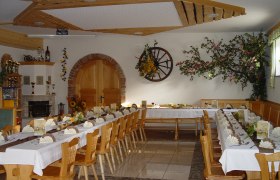 Gasthof Krenn, © zur Verfügung gestellt: Gasthof Krenn Ein festlich gedeckter Gastraum mit langen Tischen, dekoriert mit Blumen und Servietten, in einem rustikalen Ambiente.