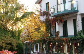 Außenansicht, © Hotel Klaus Außenansicht eines Hauses mit Efeu bewachsen und Herbstbäumen im Hintergrund.