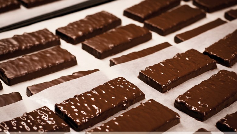 Konditorei Hagmann, © Konditorei Hagmann Schokoladenüberzogene Kekse auf Backpapier in einer Konditorei.