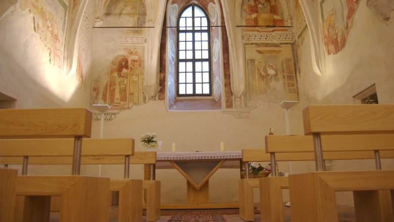 Schlosskapelle, © Stadtgemeinde Amstetten Innenansicht einer Schlosskapelle mit Fresken, Holzbänken und einem Altar.